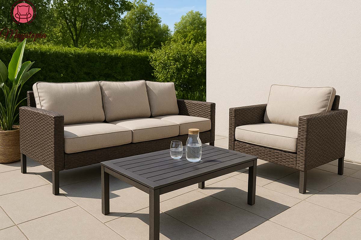 Stylish outdoor patio with a dark brown rattan sofa set, beige cushions, and a matching armchair beside a modern coffee table, surrounded by greenery under bright sunlight.
