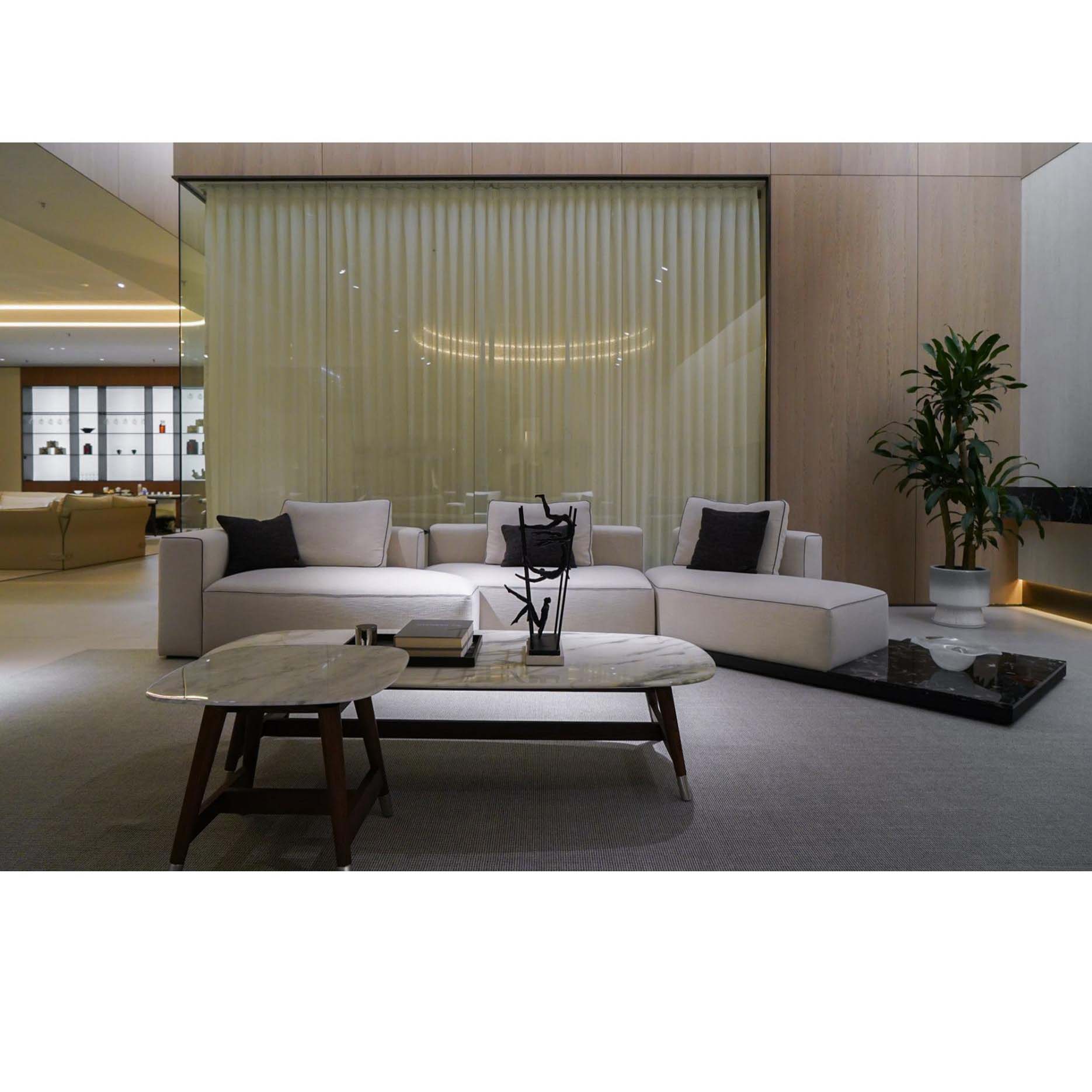 Italian-style loveseat in a modern showroom corner with warm lighting and greenery.