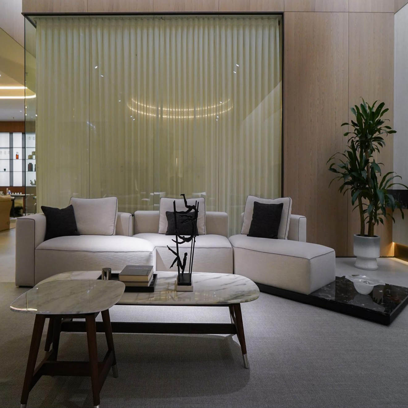 Lounge area of showroom with marble coffee table and modular sofa set under soft ambient lighting.