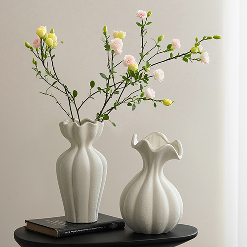 Classic white ceramic flower vases with yellow and green floral branches on black table